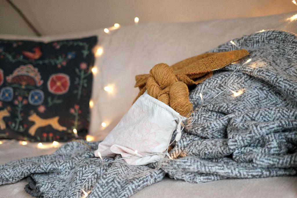 Close-up of hands knitting intricate cable and lace pattern on luxury throw